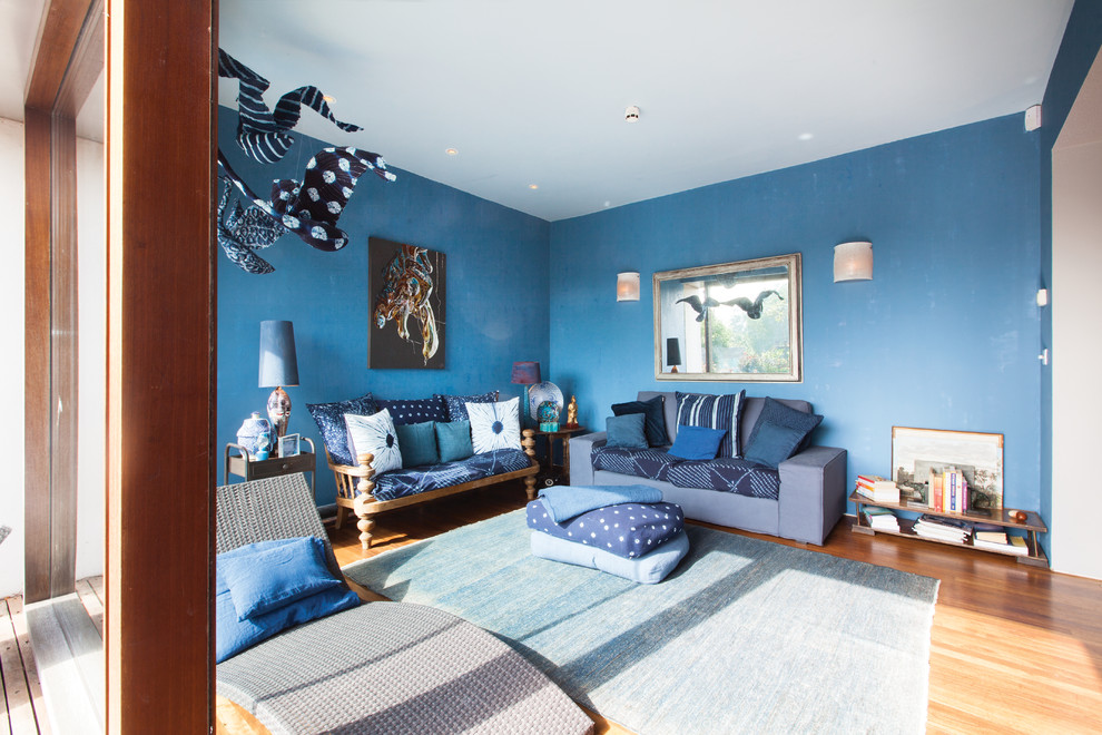 Diseño de salón abierto bohemio de tamaño medio con paredes azules y suelo de madera en tonos medios