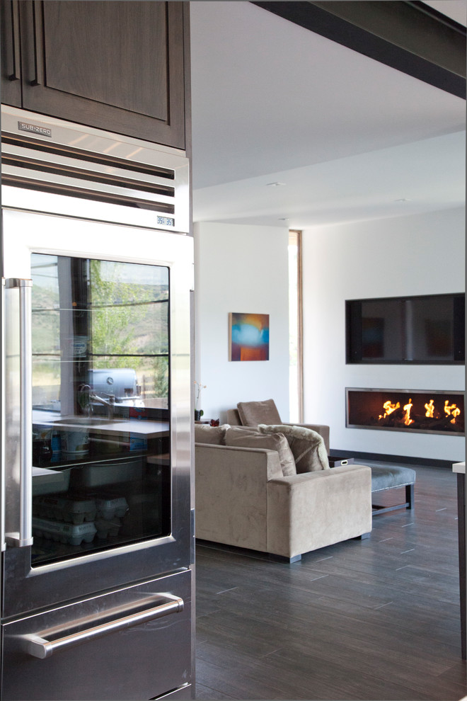 This is an example of a medium sized contemporary open plan living room in Denver with white walls, dark hardwood flooring, a ribbon fireplace, a metal fireplace surround, a wall mounted tv and brown floors.