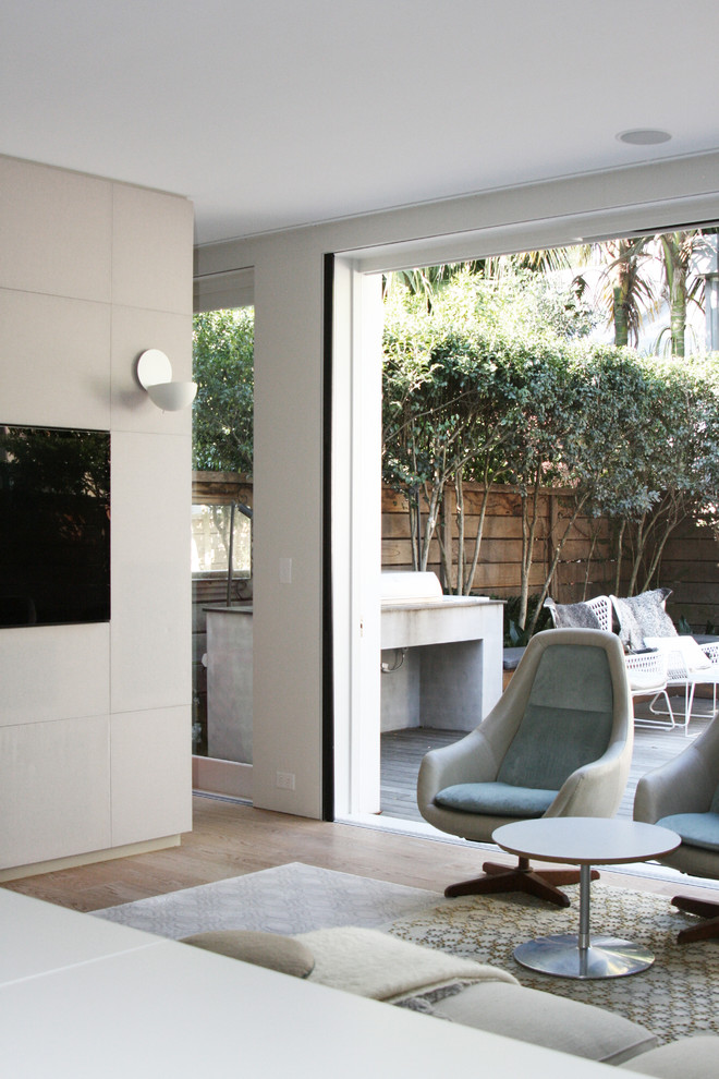 Cette image montre un salon design de taille moyenne et ouvert avec un mur blanc, parquet clair, un téléviseur fixé au mur et un sol marron.