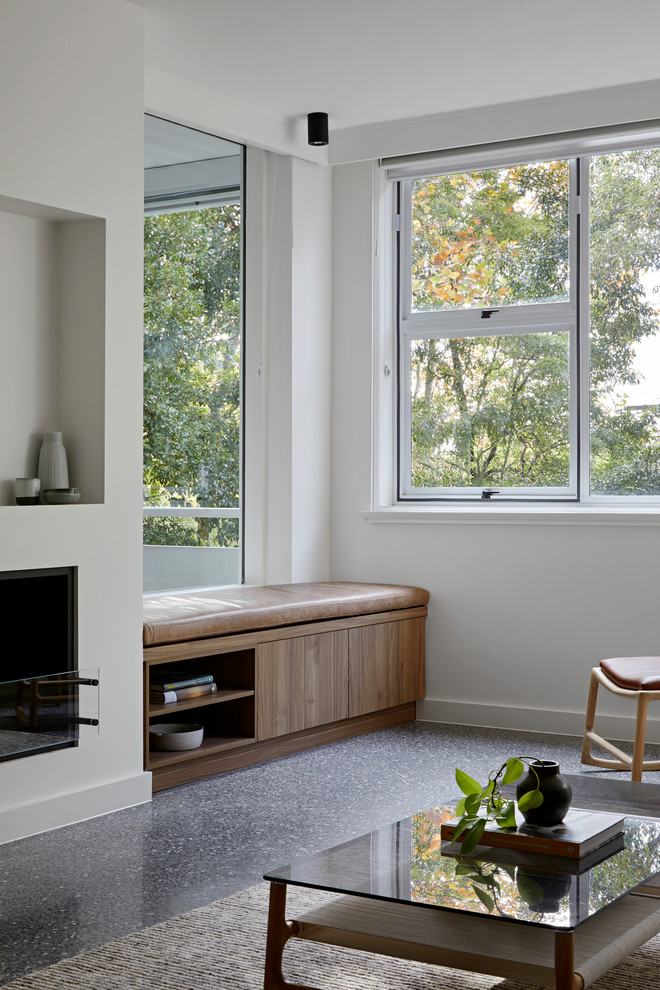 Inspiration pour un petit salon design fermé avec un mur blanc, sol en béton ciré, une cheminée standard, un manteau de cheminée en plâtre, un téléviseur encastré et un sol gris.