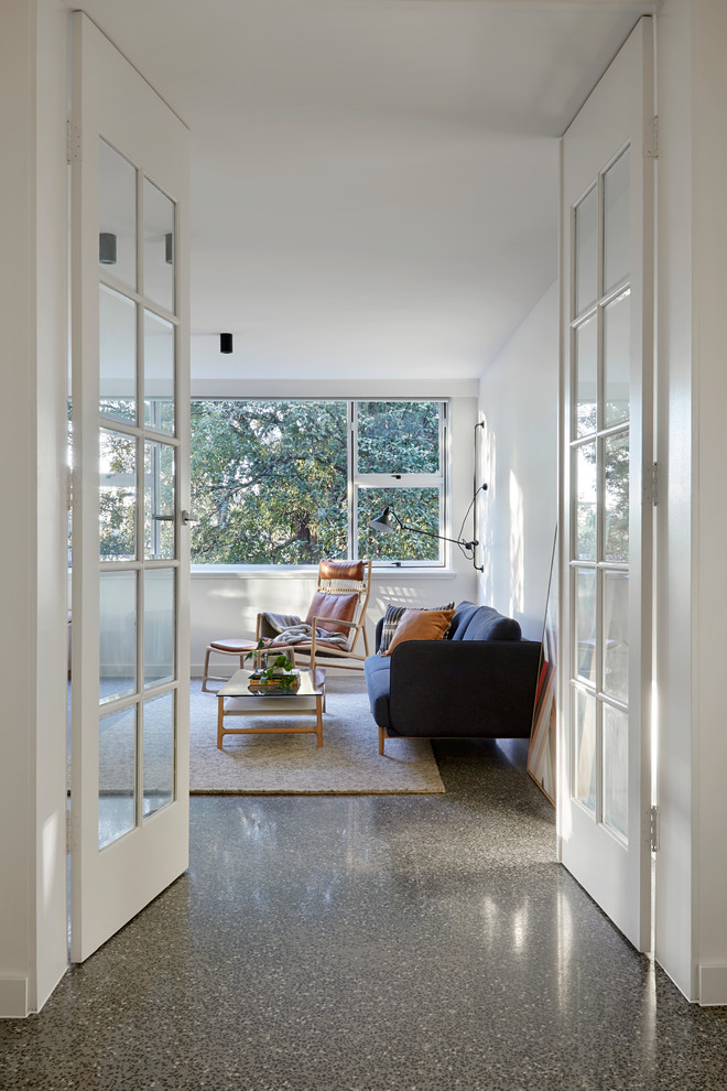 Kleines, Abgetrenntes Modernes Wohnzimmer mit weißer Wandfarbe, Betonboden, Kamin, verputzter Kaminumrandung, Multimediawand und grauem Boden in Melbourne