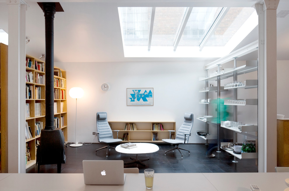 Imagen de biblioteca en casa contemporánea de tamaño medio con paredes blancas y estufa de leña