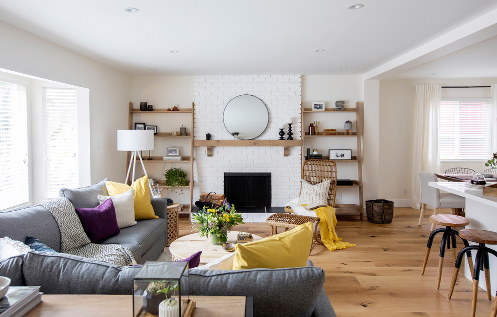 Cette photo montre un salon chic avec un mur beige, un sol en bois brun, une cheminée standard, un manteau de cheminée en brique et un sol marron.