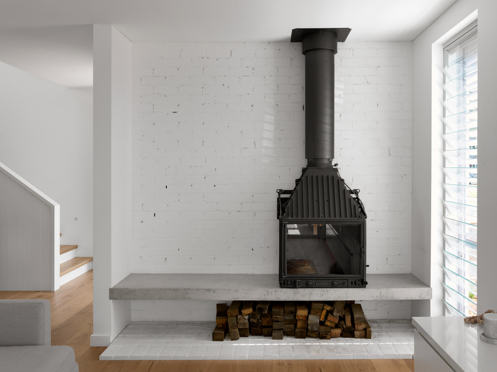 Foto de salón costero con estufa de leña y marco de chimenea de ladrillo