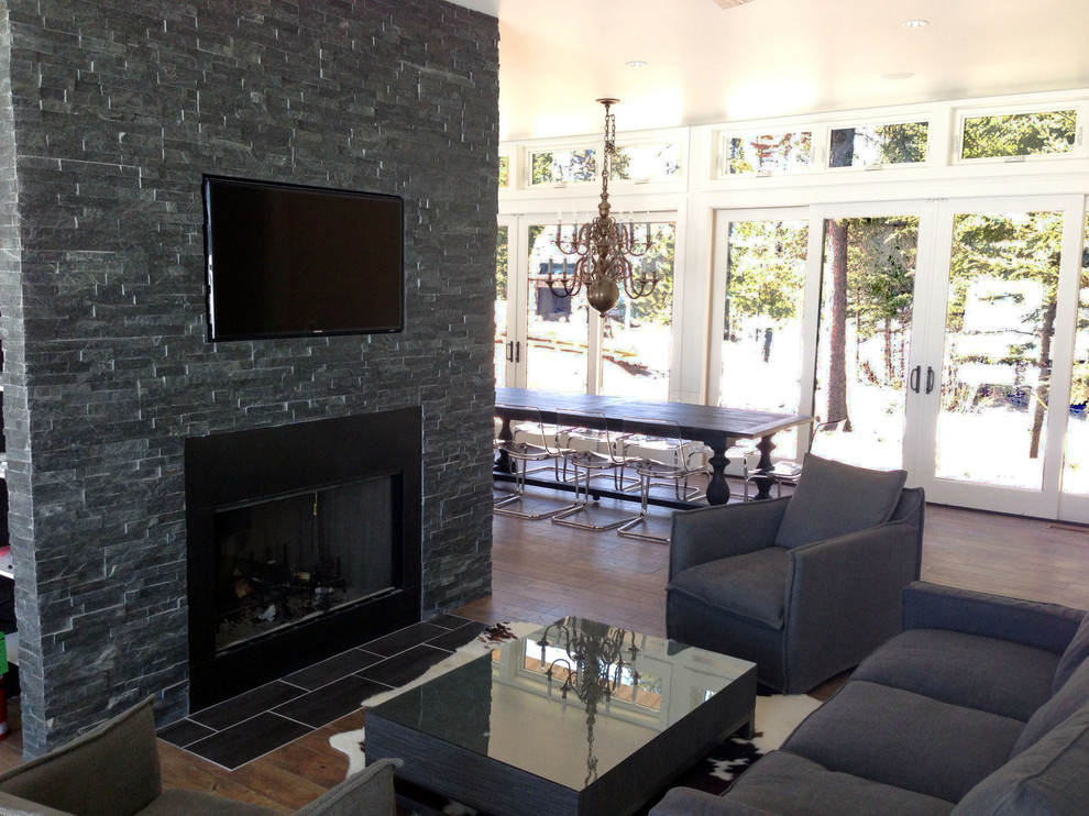 Example of a minimalist open concept dark wood floor living room design in Toronto with white walls, a standard fireplace, a stone fireplace and a media wall