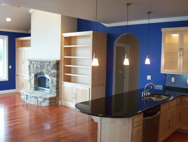 Idee per un ampio soggiorno moderno aperto con pareti blu, pavimento in legno massello medio, camino classico, cornice del camino in pietra e TV nascosta