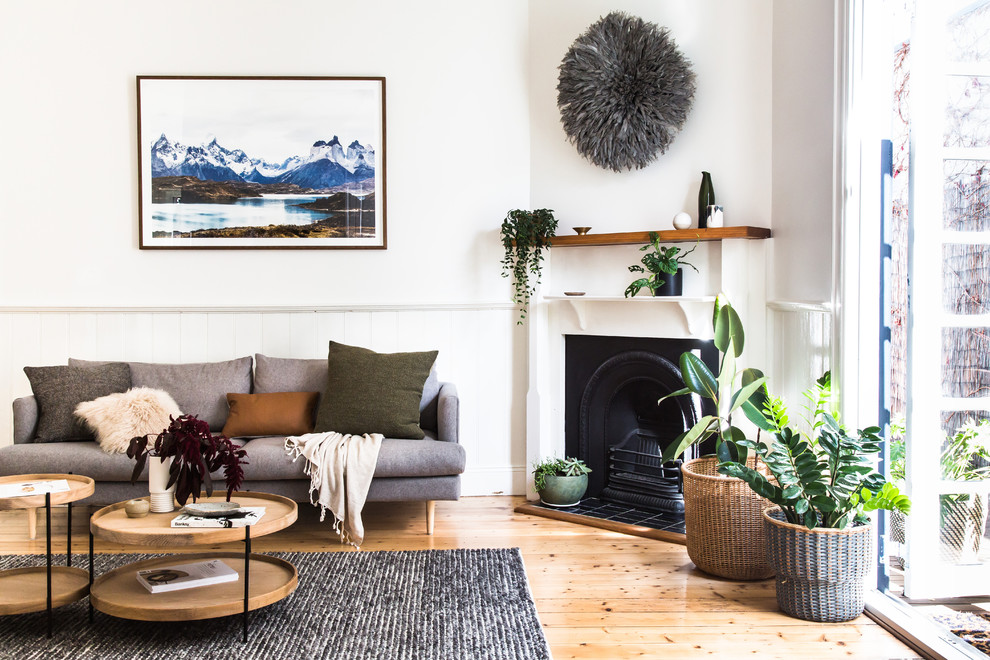 Cette image montre un salon design ouvert avec un mur blanc, parquet clair, une cheminée standard, un manteau de cheminée en métal et un sol marron.
