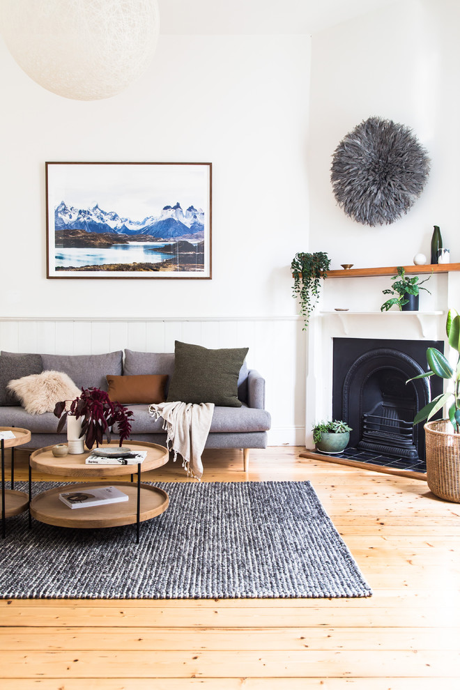 Offenes Modernes Wohnzimmer mit weißer Wandfarbe, hellem Holzboden, Kamin, Kaminumrandung aus Metall, freistehendem TV und braunem Boden in Melbourne