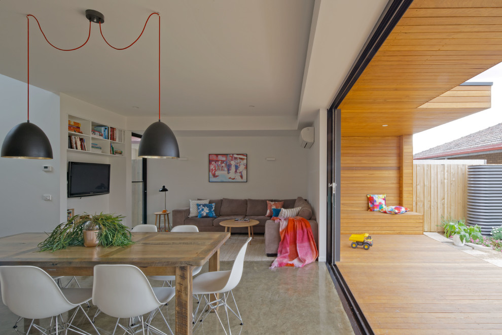 Immagine di un piccolo soggiorno contemporaneo aperto con pareti bianche, pavimento in cemento e TV a parete