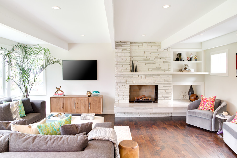 Foto de salón abierto actual de tamaño medio con paredes blancas, chimenea de esquina, marco de chimenea de piedra, televisor colgado en la pared y suelo laminado