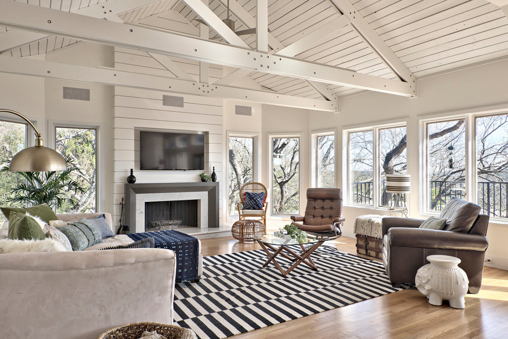 Offenes Landhausstil Wohnzimmer mit weißer Wandfarbe, hellem Holzboden, Kamin, Kaminumrandung aus Holz, TV-Wand und beigem Boden in Austin