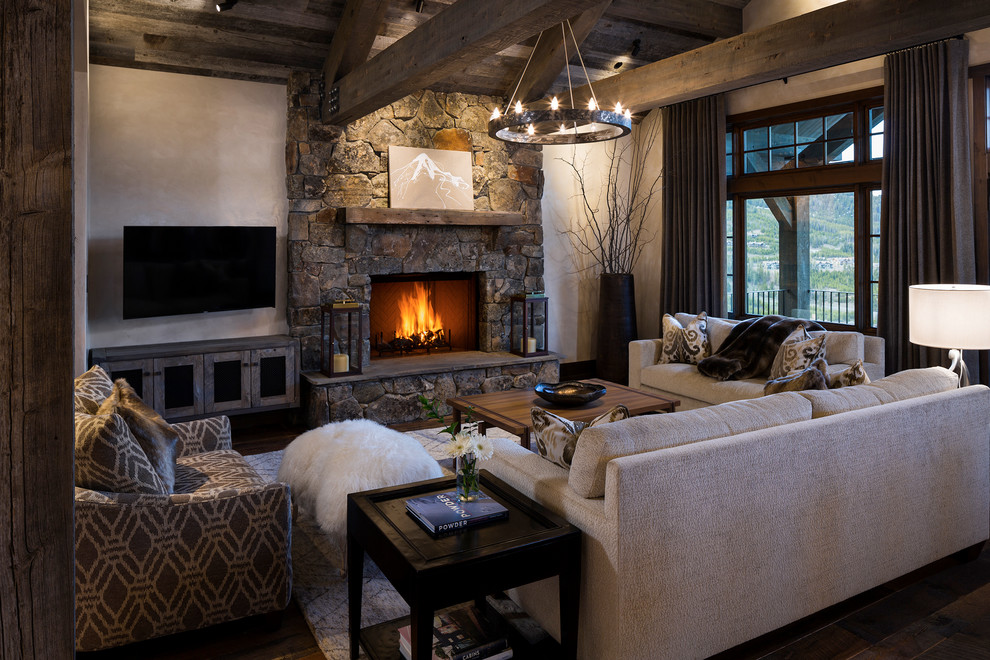 This is an example of a rustic living room in Other with beige walls, dark hardwood flooring, a stone fireplace surround, a wall mounted tv and a standard fireplace.