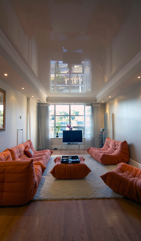 Esempio di un soggiorno design di medie dimensioni e aperto con pareti beige, pavimento in legno massello medio, nessun camino e TV autoportante