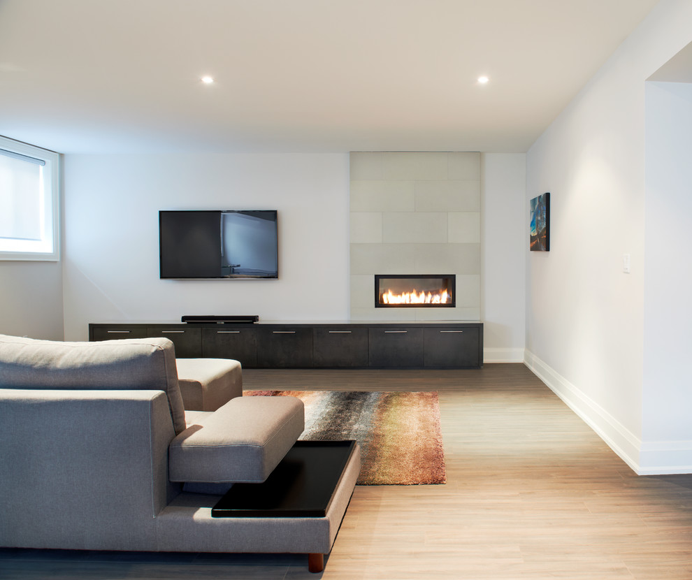 Example of a mid-sized trendy open concept light wood floor and brown floor living room design in Toronto with a concrete fireplace, white walls, a standard fireplace and a wall-mounted tv