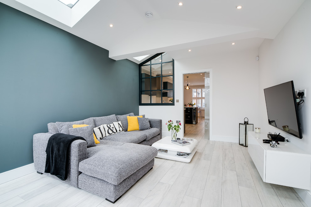 Modernes Wohnzimmer mit weißer Wandfarbe, gebeiztem Holzboden, TV-Wand und weißem Boden in London