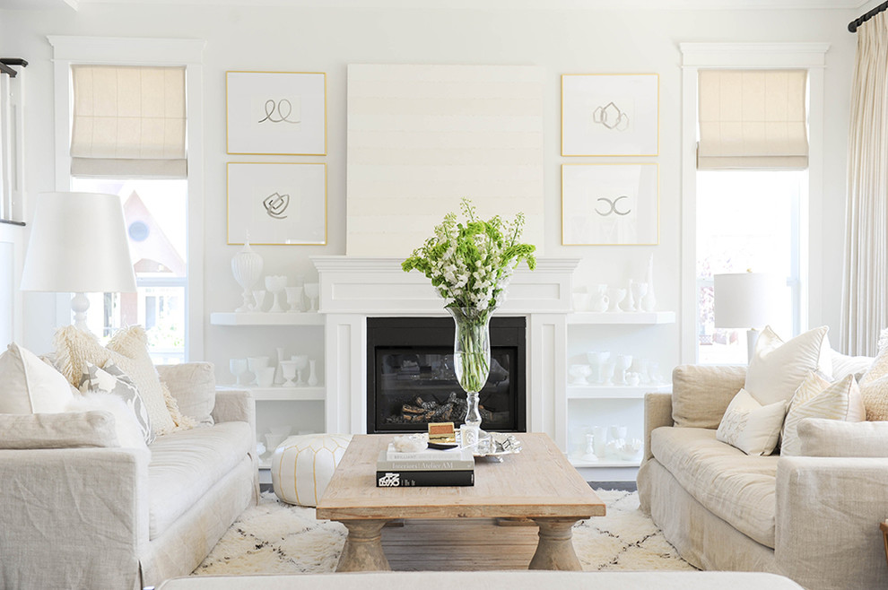 Пример оригинального дизайна: открытая гостиная комната в стиле неоклассика (современная классика) с белыми стенами, стандартным камином и фасадом камина из дерева
