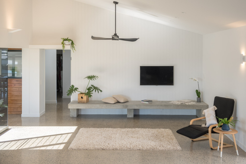 На фото: открытая гостиная комната среднего размера в стиле модернизм с белыми стенами, бетонным полом, телевизором на стене, серым полом, сводчатым потолком и панелями на части стены
