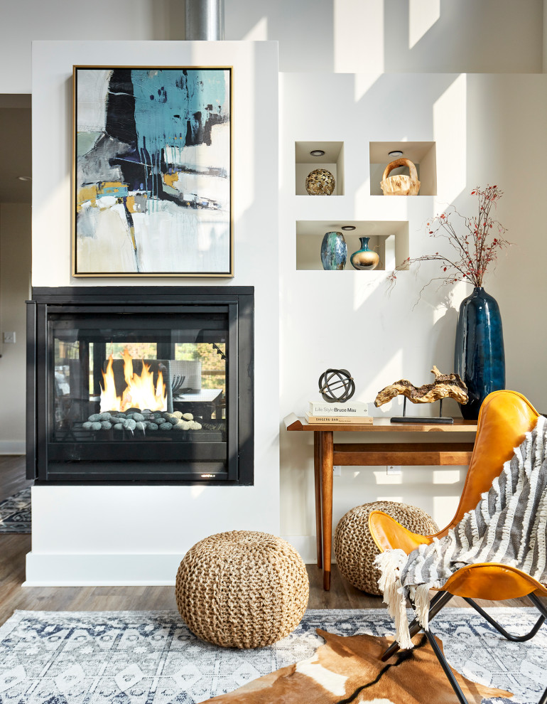 Foto de salón abierto moderno pequeño sin televisor con paredes blancas, suelo de madera en tonos medios, chimenea de doble cara, marco de chimenea de yeso y suelo marrón