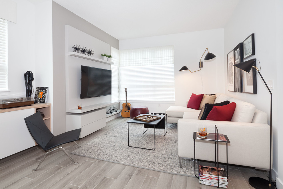 Foto på ett minimalistiskt allrum med öppen planlösning, med vita väggar, ljust trägolv och en väggmonterad TV