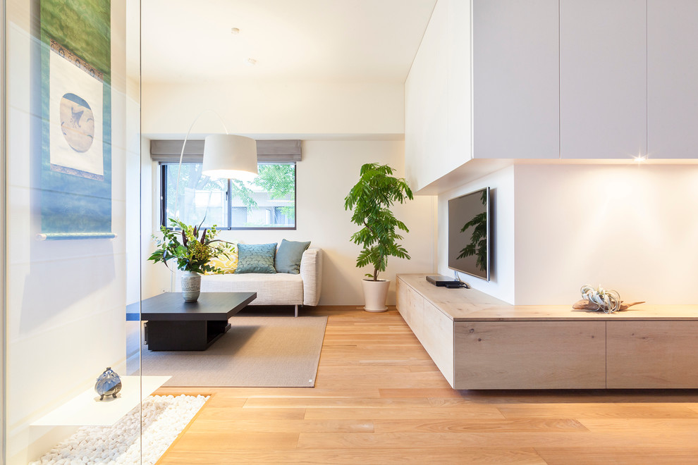 Ispirazione per un soggiorno moderno di medie dimensioni e aperto con pareti bianche, pavimento in legno massello medio e TV a parete