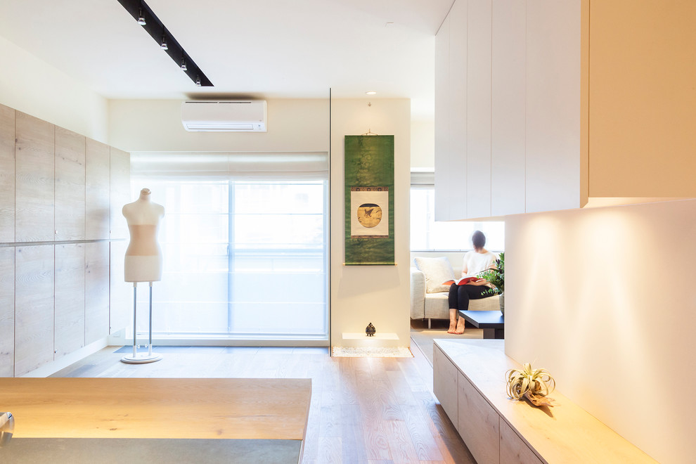 Modelo de salón para visitas abierto minimalista de tamaño medio sin chimenea con paredes blancas, suelo de madera en tonos medios y televisor colgado en la pared