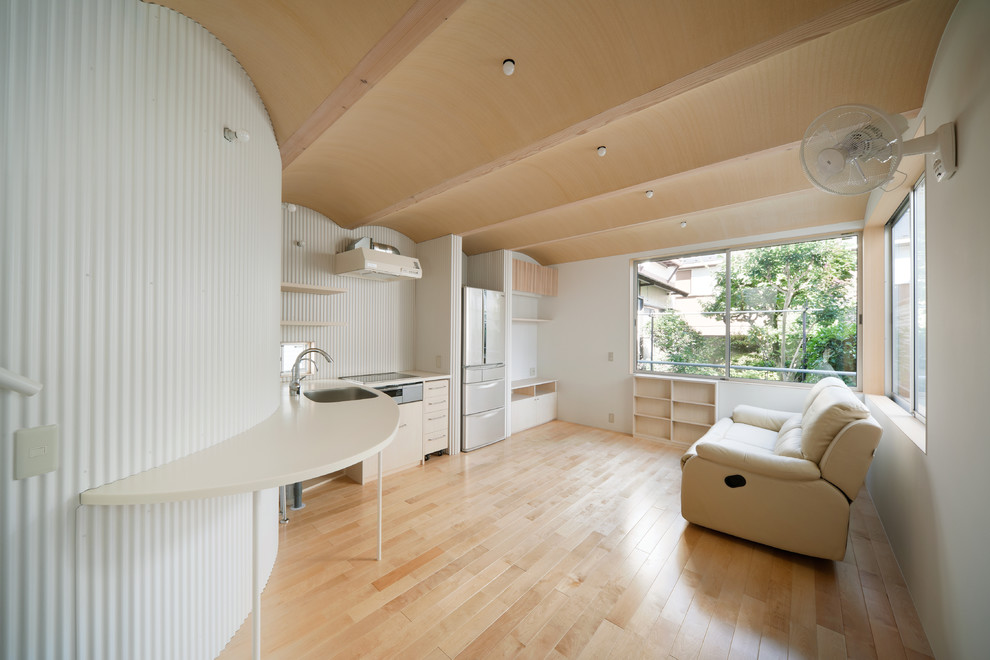 Exempel på ett litet minimalistiskt allrum med öppen planlösning, med vita väggar, ljust trägolv, en fristående TV och beiget golv