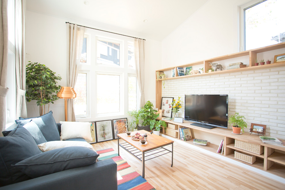 На фото: гостиная комната в современном стиле с белыми стенами, светлым паркетным полом, отдельно стоящим телевизором и красивыми шторами с