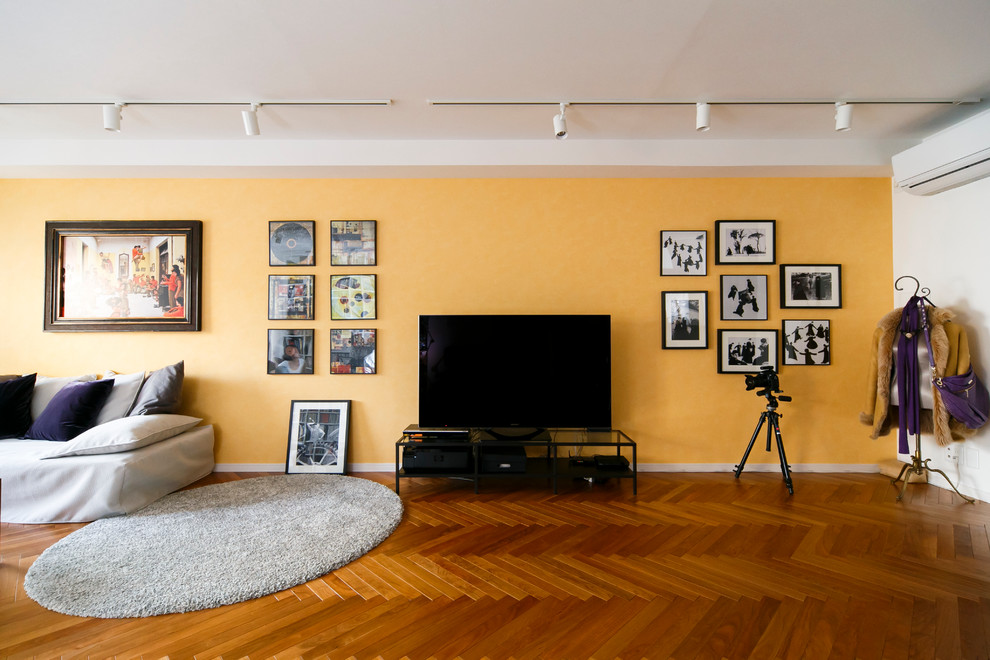 Idee per un soggiorno minimalista con pareti arancioni, parquet scuro e TV autoportante