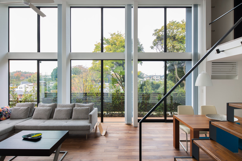 Cette photo montre un salon moderne ouvert avec un mur blanc et un sol en bois brun.