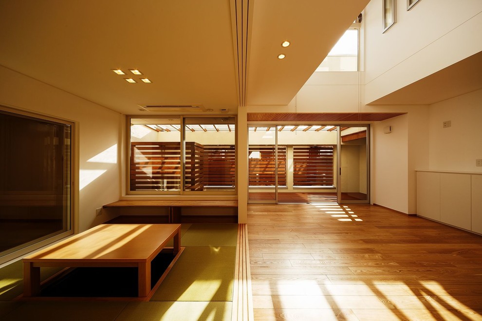 Large world-inspired open plan living room in Osaka with white walls, light hardwood flooring, a corner tv and beige floors.