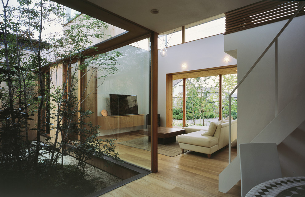 Idéer för ett modernt vardagsrum, med vita väggar, ljust trägolv och en fristående TV
