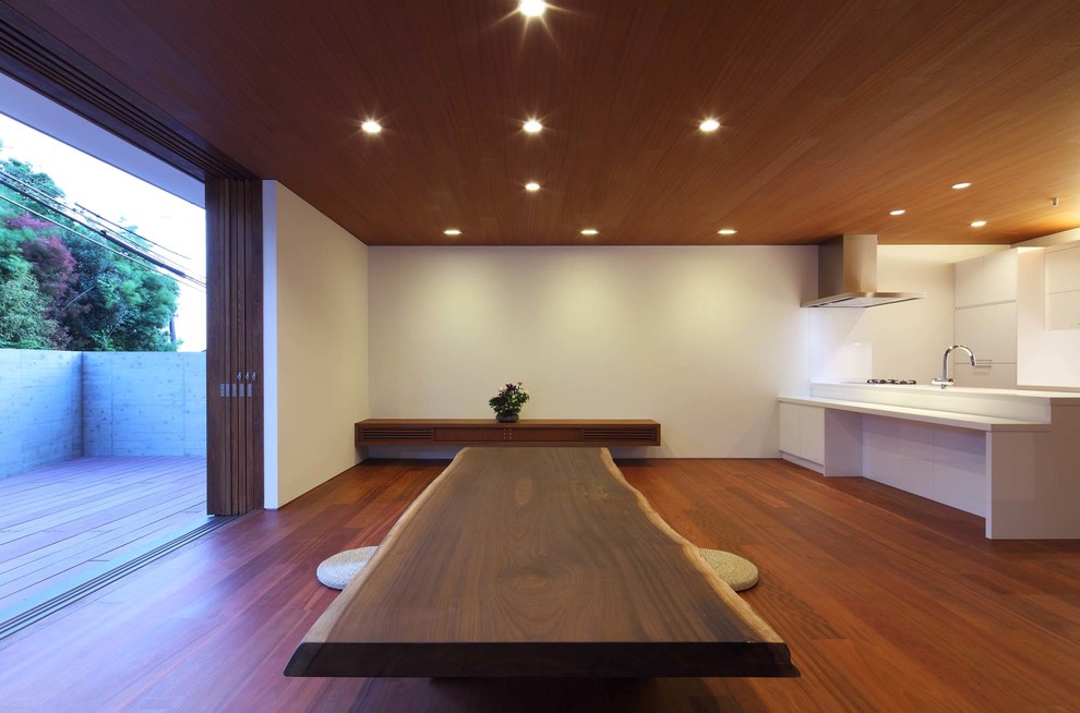 Modelo de salón moderno sin chimenea con paredes blancas, suelo de madera en tonos medios y suelo marrón