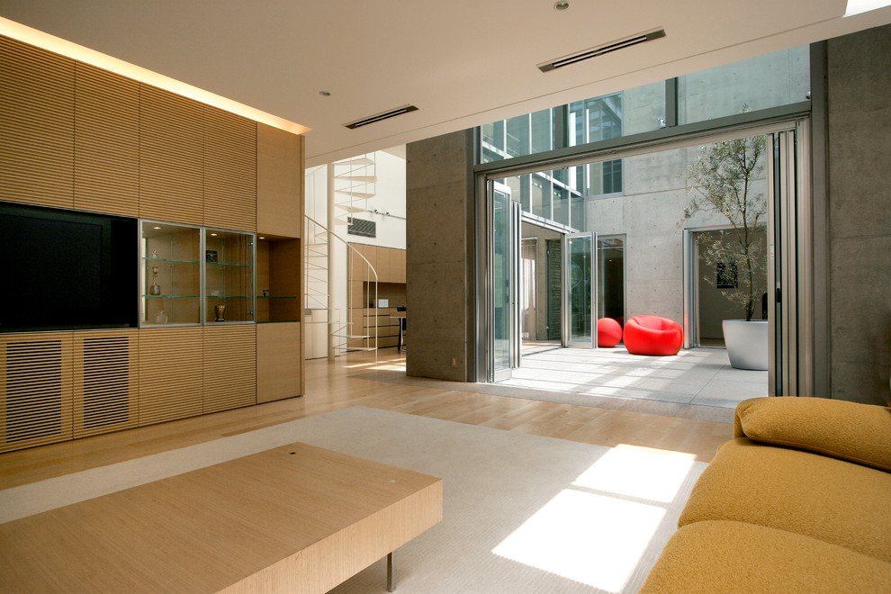 Aménagement d'un très grand salon moderne avec parquet clair, un téléviseur fixé au mur et un sol beige.