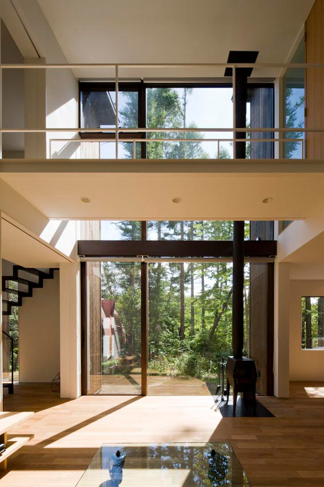 Immagine di un soggiorno design aperto con pavimento in legno massello medio e stufa a legna