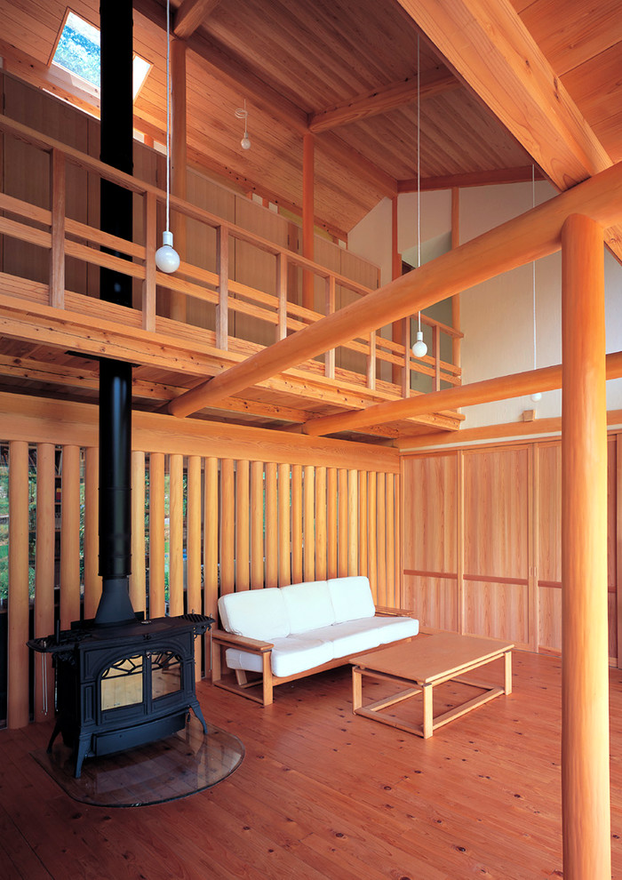 Idee per un soggiorno etnico con pareti beige, pavimento in legno massello medio, stufa a legna e cornice del camino in legno