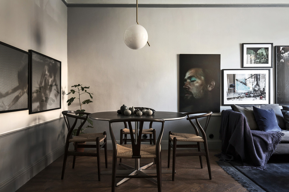 На фото: столовая среднего размера в скандинавском стиле с серыми стенами и темным паркетным полом без камина с