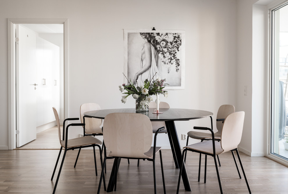 Cette photo montre une salle à manger scandinave fermée avec un mur blanc, un sol marron et parquet clair.