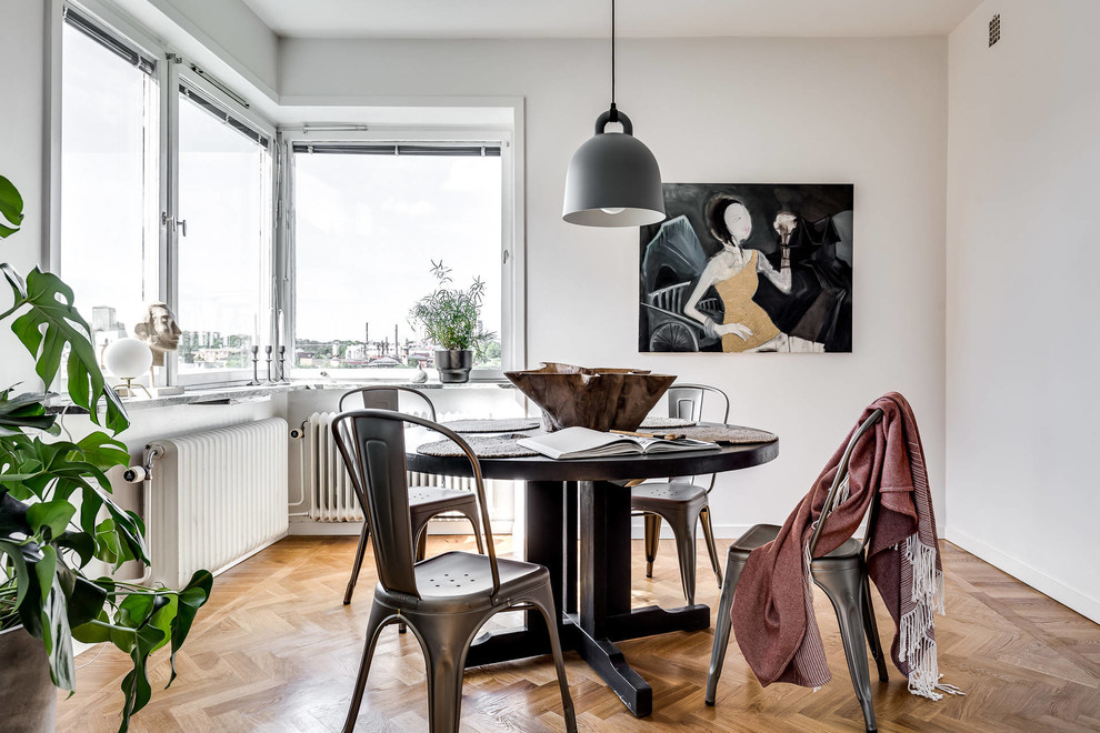 Medium sized urban dining room in Stockholm with white walls and medium hardwood flooring.