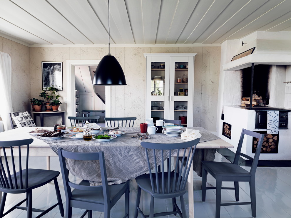 Idée de décoration pour une salle à manger champêtre de taille moyenne avec un mur beige, parquet peint, une cheminée standard et un manteau de cheminée en pierre.