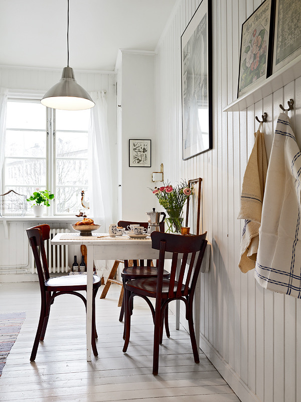 Immagine di una sala da pranzo aperta verso la cucina country con pareti bianche, pavimento in legno verniciato e pavimento bianco