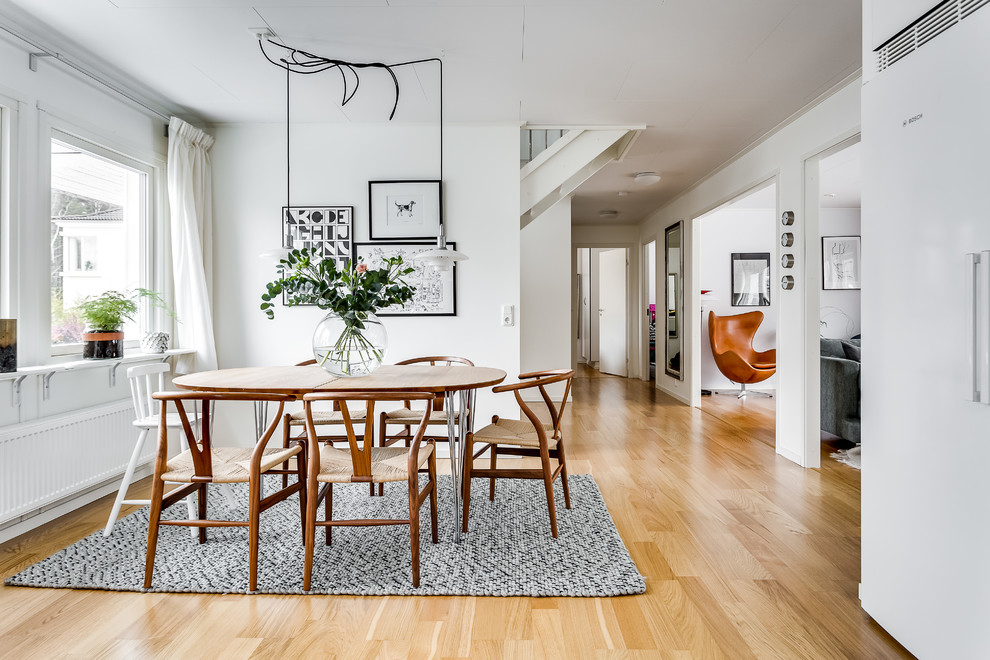 Foto di una sala da pranzo nordica con pareti bianche, parquet chiaro e pavimento beige