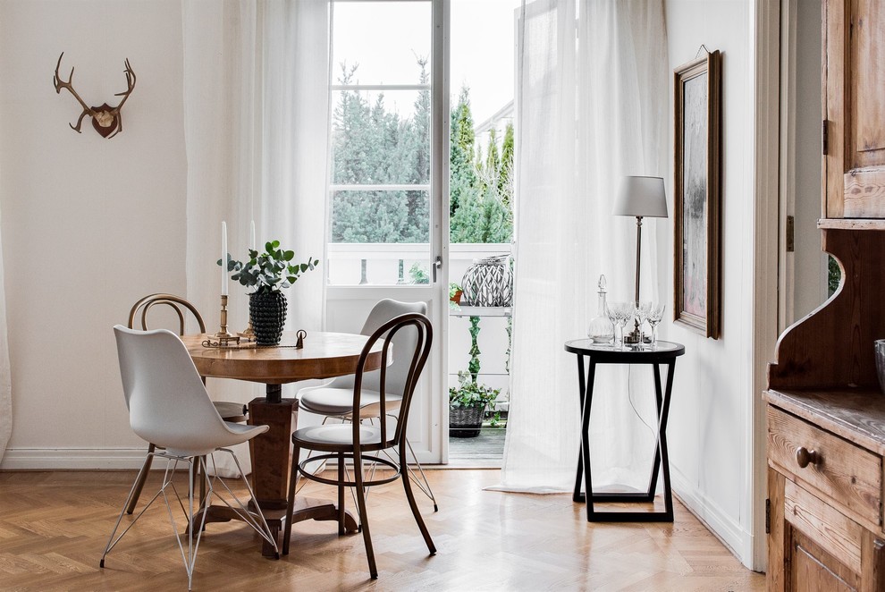 На фото: столовая в скандинавском стиле с белыми стенами, паркетным полом среднего тона и коричневым полом