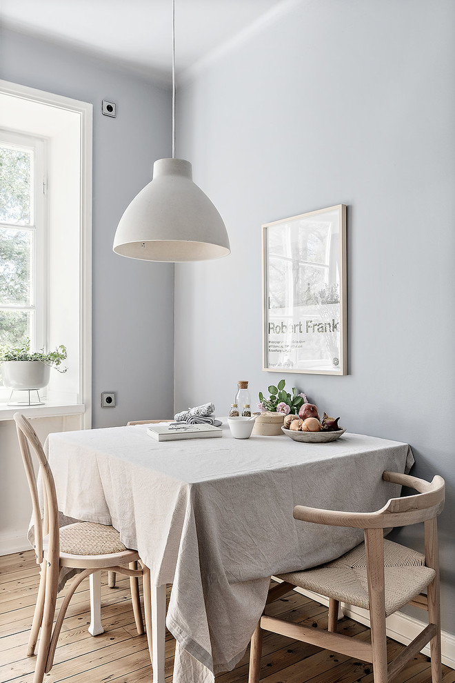 Small scandi dining room in Stockholm with grey walls, light hardwood flooring and beige floors.