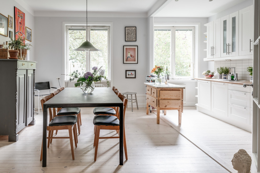 Immagine di una sala da pranzo aperta verso la cucina scandinava di medie dimensioni con pareti grigie, parquet chiaro, nessun camino e pavimento beige