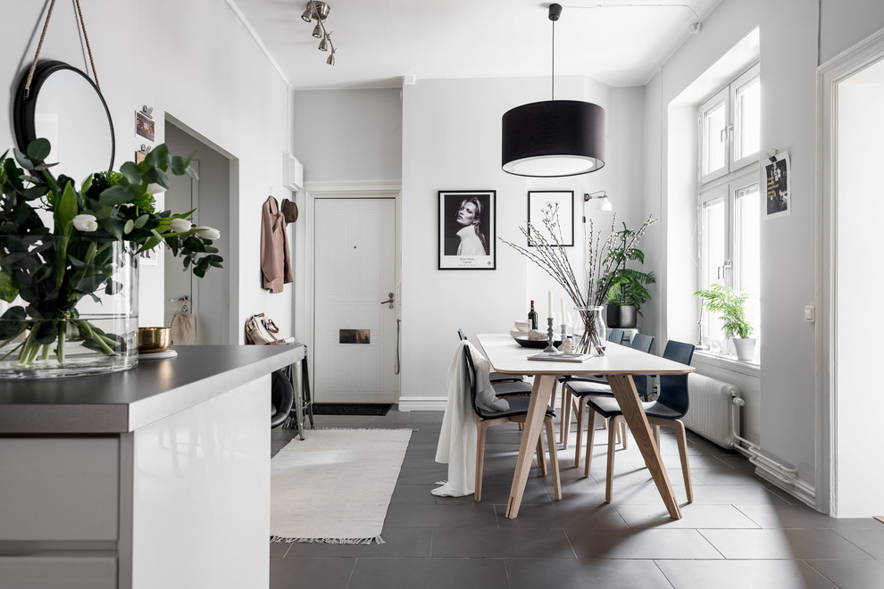 Cette photo montre une petite salle à manger ouverte sur la cuisine scandinave avec un mur blanc, un sol noir, sol en béton ciré et aucune cheminée.