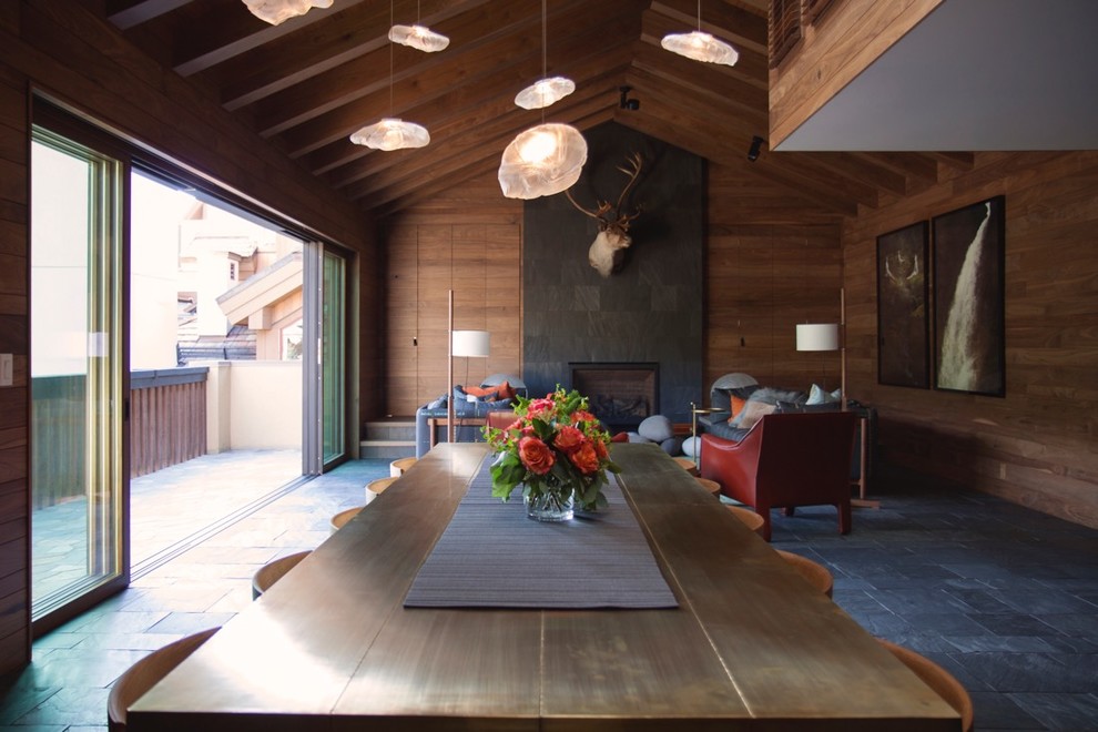 Esempio di un'ampia sala da pranzo aperta verso il soggiorno minimalista con pavimento in ardesia, camino classico, cornice del camino in pietra e pavimento grigio