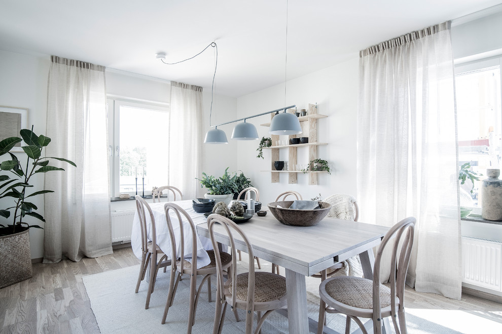 This is an example of a medium sized scandi dining room in Stockholm with white walls, light hardwood flooring, no fireplace and beige floors.