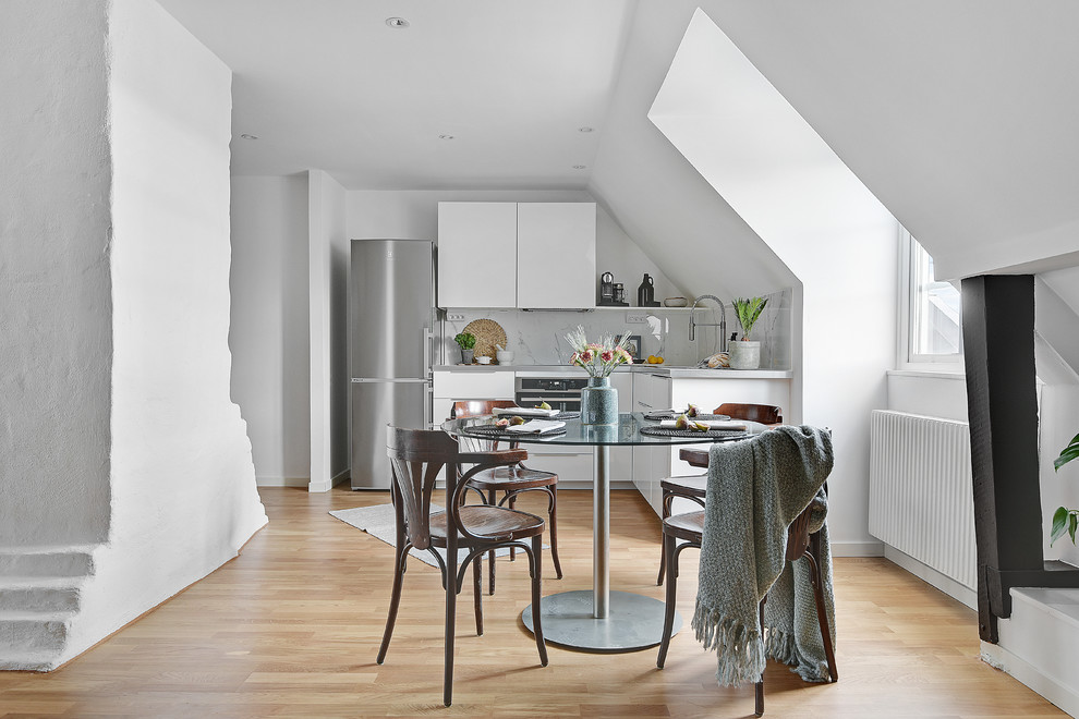 Cette image montre une salle à manger ouverte sur la cuisine nordique de taille moyenne avec un mur blanc, un sol beige et parquet clair.