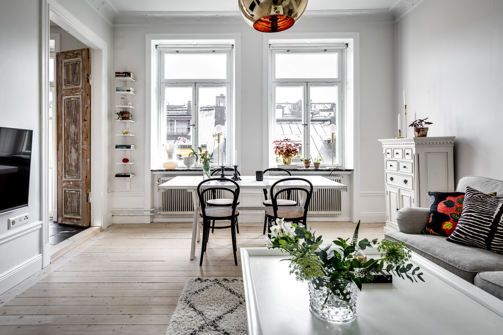 На фото: столовая среднего размера в скандинавском стиле с белыми стенами