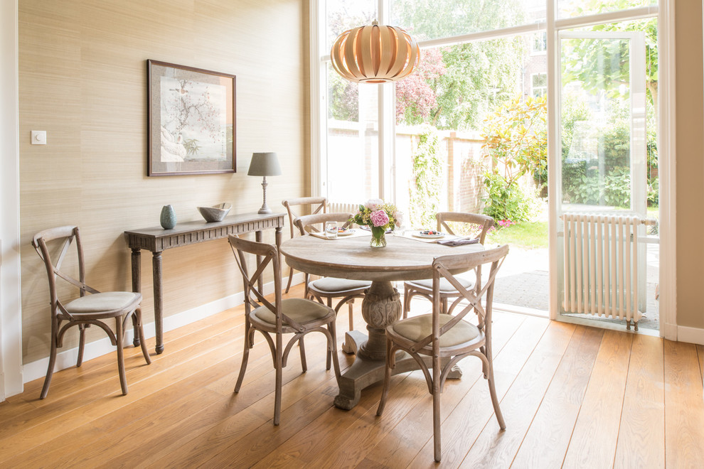 Immagine di una sala da pranzo scandinava con pareti beige, pavimento in legno massello medio e nessun camino
